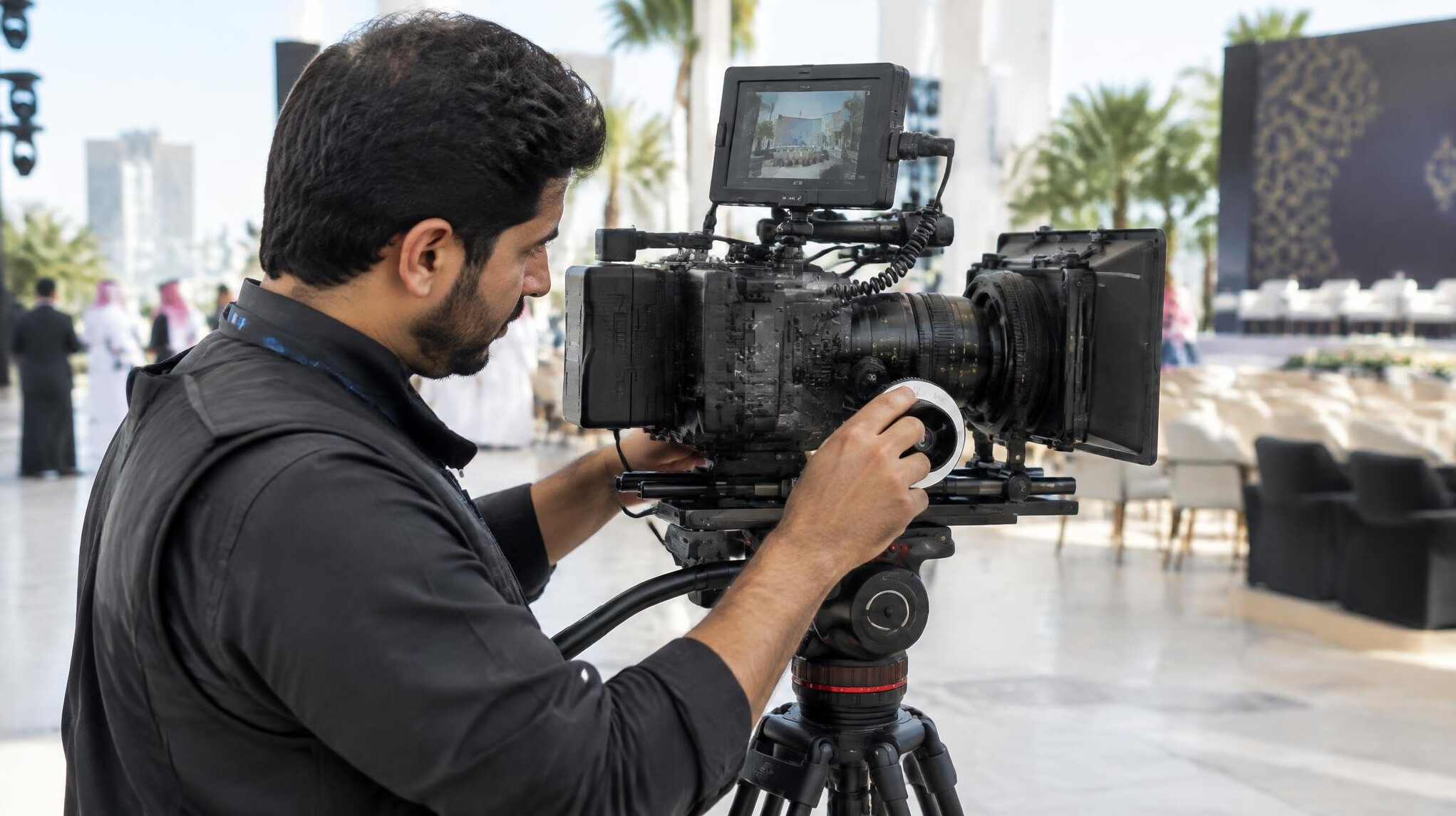 Technician adjusting a professional video camera on a tripod
